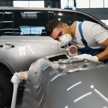 Auto Body Repair Near Me.-Auto body technician sanding a bumper during professional collision repair in Josephine, TX.