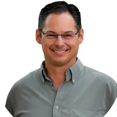 Auto Body Shop Josephine TX – Smiling man with short dark hair and glasses wearing a gray button-up shirt.